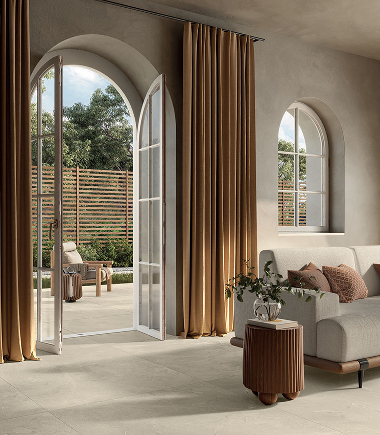 Contemporary living room with stone-effect porcelain stoneware flooring, natural tones and large openings to the outdoors for an elegant, light-filled space.
