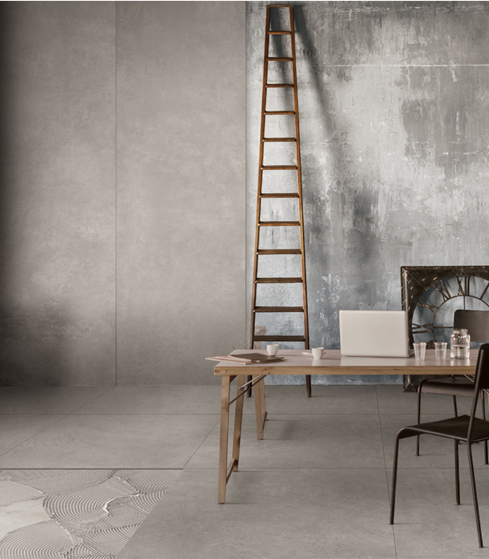 Industrial-style office space with concrete-effect flooring, textured walls, wooden staircase, and minimalist furnishings in wood and metal.