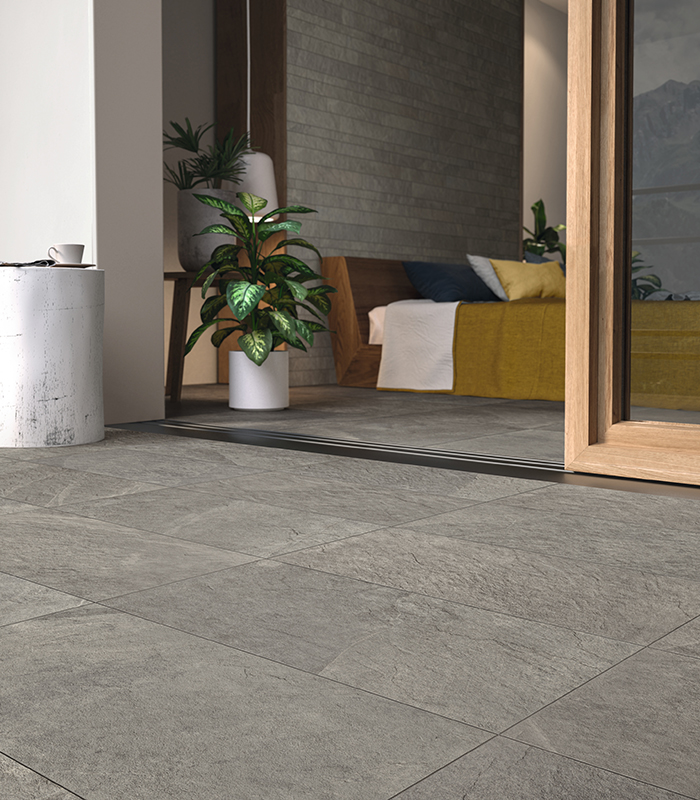 Top view of a modern kitchen with a dinette island covered with light grey stone-effect stoneware slabs and dark wood-effect porcelain stoneware floor tiles.