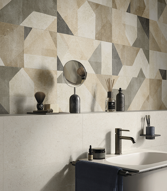 Washbasin wall of a small bathroom with light stone-effect porcelain stoneware, featuring a 120 cm high shelf and multicolour decorative tiles with geometric patterns.