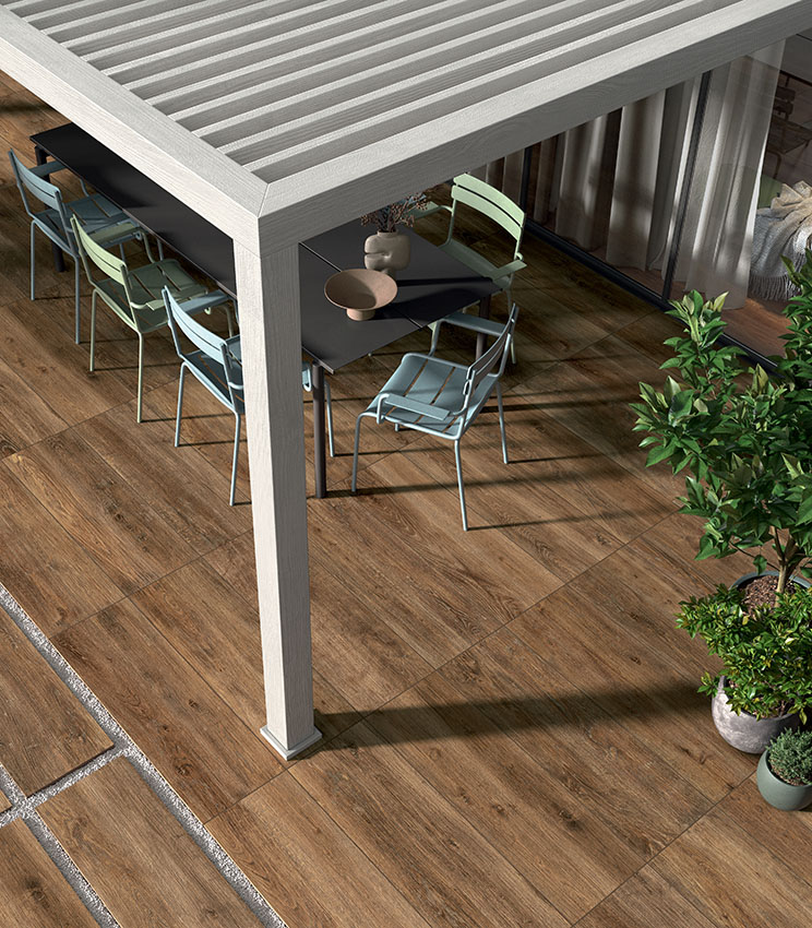 Outdoor patio with wood-effect porcelain stoneware flooring, contemporary furnishings and a pergola, creating a welcoming, durable and natural-looking space.