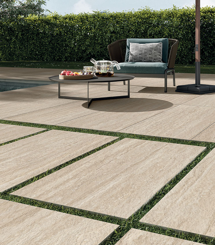 Near ground-level view of a 20 mm outdoor porcelain stoneware floor in a travertine effect in front of a swimming pool | Perpetual Travertino collection by Panaria Ceramica