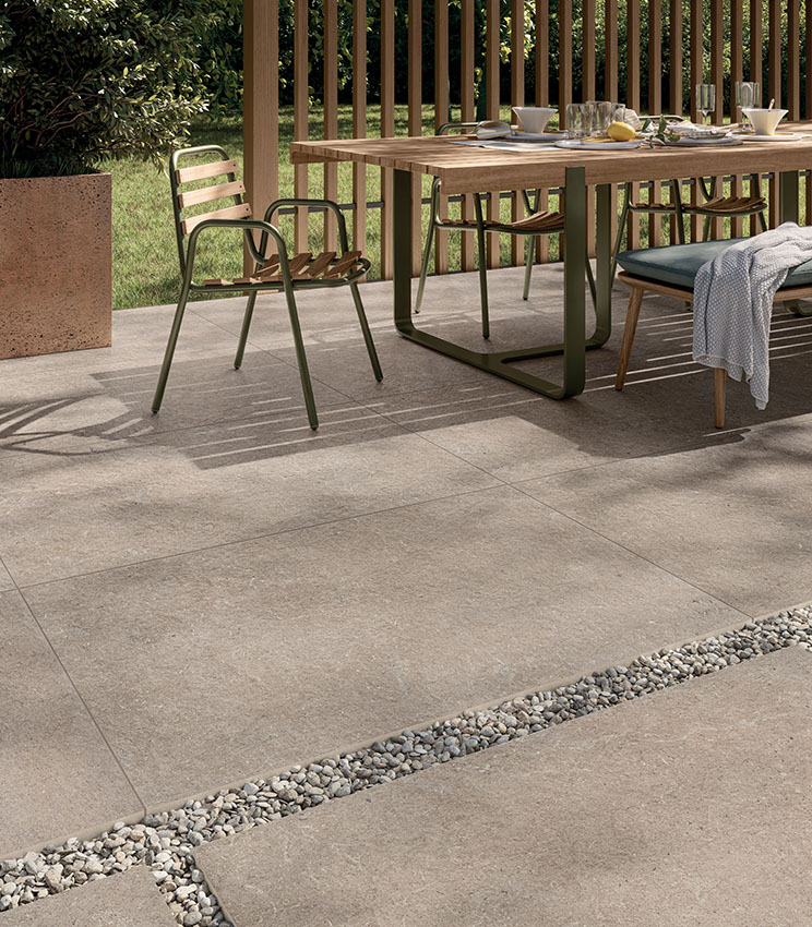 View of a breakfast patio laid with 20 mm outdoor stone-effect porcelain stoneware in a sand colour, partly adhesive-laid and partly dry-laid on gravel | Surround collection by Panaria Ceramica