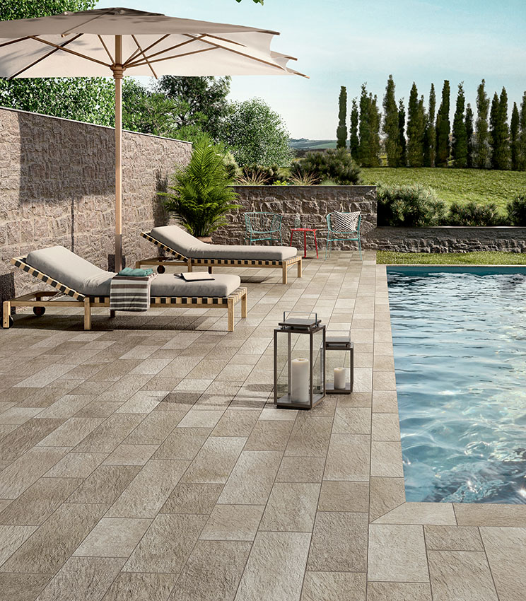 Poolside area with stone-effect porcelain stoneware flooring, sun loungers and outdoor furnishings, creating an elegant, natural-looking and durable space.